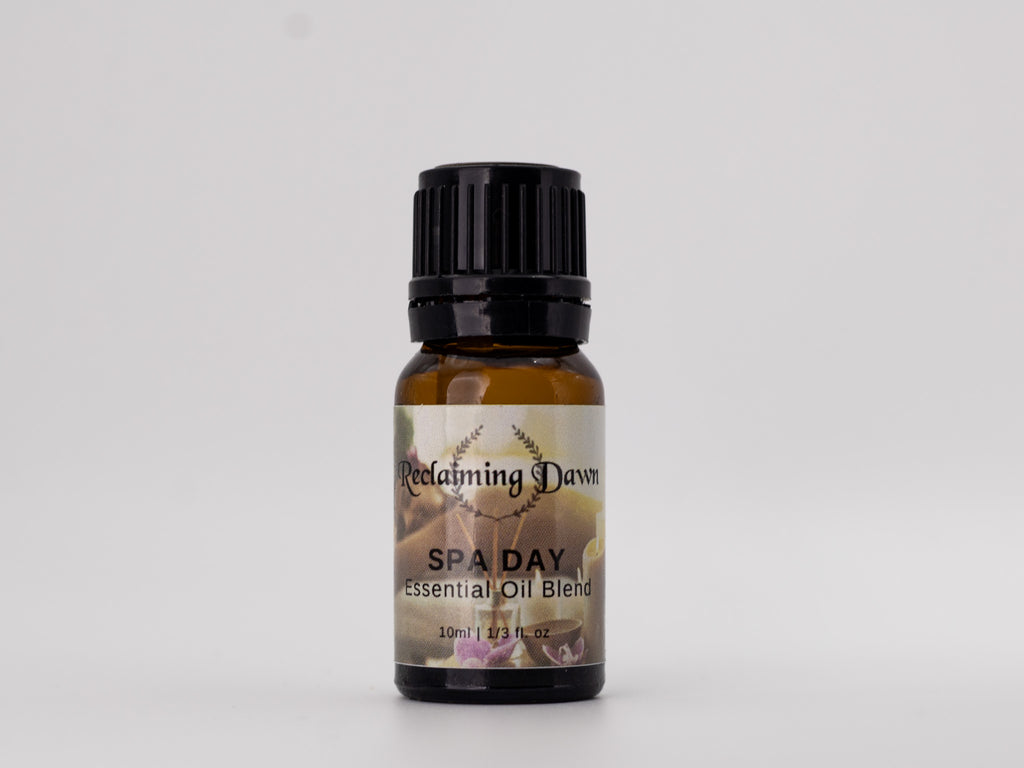 Essential oil blend bottle labeled 'Spa Day' by 'Reclaiming Dawn' on a light gray background