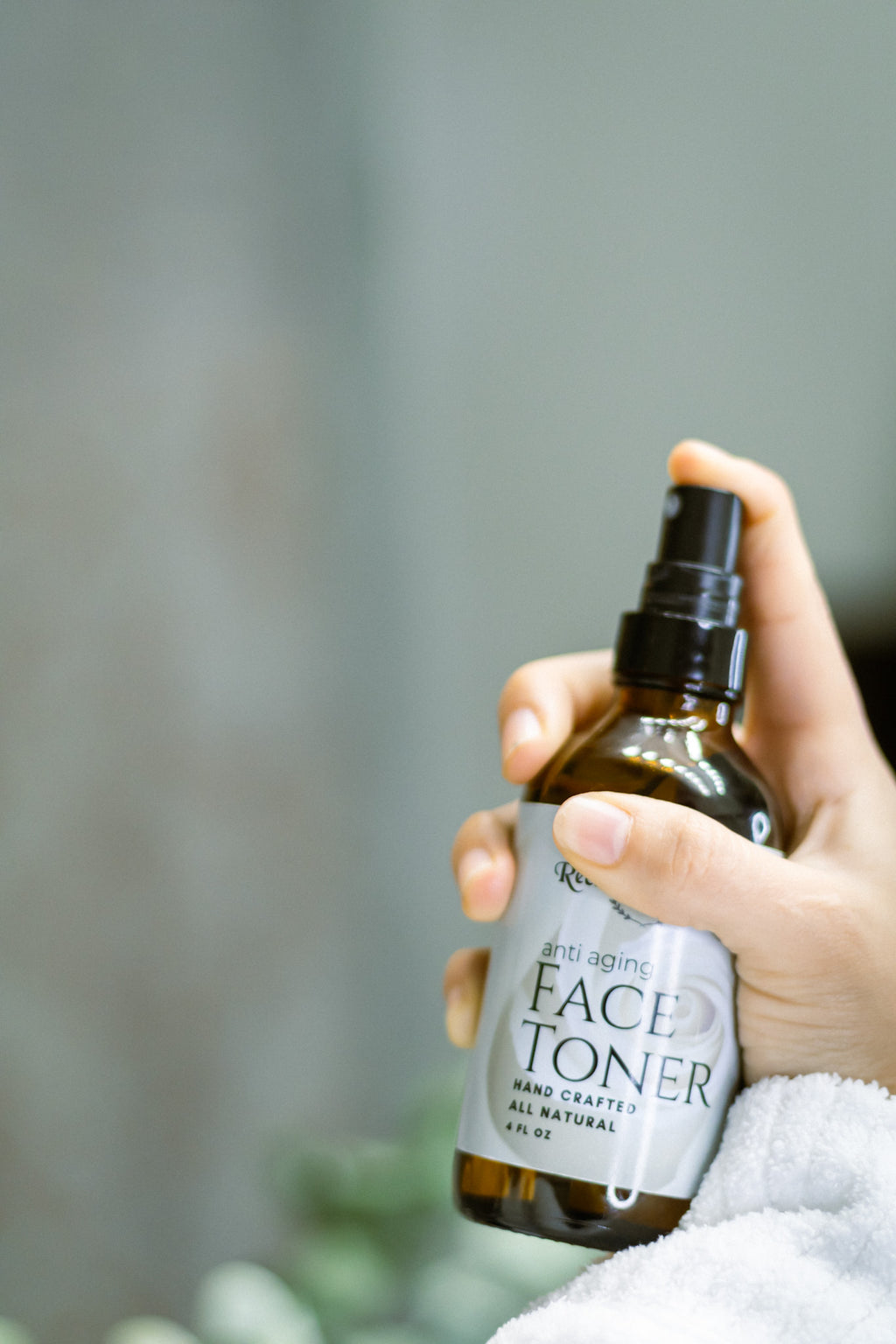 Hand holding a bottle of face toner with a blurred background